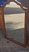 Full view of framed mirror showing the arch-shaped top and rectangular glass surface on a wood finish frame.