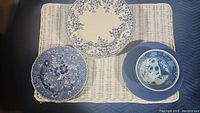 Top view showing Johnson Brothers plates with blue floral pattern along with solid blue plates and a small decorative bowl.