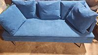 Full view of blue sofa with five pillows arranged on it