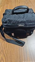 Black Nikon branded camera carrying case with handle and strap shown from the front.