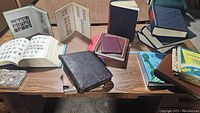 Multiple stamp albums and a stock sheet arranged on a wooden table