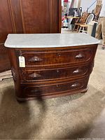 Full front view showing curved front, three drawers, marble top