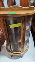 Front closed view of the vintage miniature curio cabinet showing curved glass door and wooden frame.