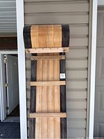 Front view of wooden toboggan leaning against siding wall showing full length and slatted seat.