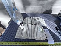 Table display showing white ceramic egg-shaped dish with rabbit figurine alongside a stack of 25 hardcover Beatrix Potter children’s books laid flat on a blue quilted surface.