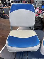 Front view of one blue and white clamp-on boat seat on table, showing vinyl upholstery and metal clamp hardware