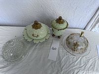 Top view showing all four covered butter dishes on a white cloth surface.