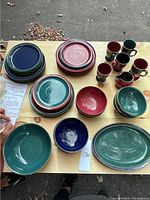 Overview of stacked dinner plates, lunch plates, bowls, mugs and creamer on wooden table