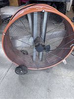 Front view showing large metal blades behind black wire grille and two small wheels underneath.