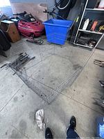 Metal dog pen assembled in an octagonal shape on a concrete floor in a garage with various other items around. Shows the pen size and foldable design.