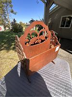Side angled view of the wooden magazine rack showing cut out decorative pattern and the overall shape