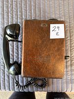 Top view of the vintage wooden telephone showing handset attached and wood grain with label.
