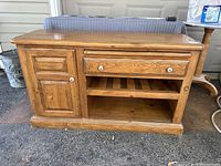 Front view of pine wood TV stand showing cabinet door, drawer, and open slatted shelves.