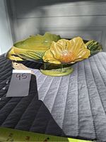 Side angle showing the yellow glaze, flower motif, and scalloped edges of the Roseville pottery bowl.