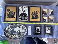 Full view of all nine silhouette prints plus decorative metal tray arranged on a cloth surface