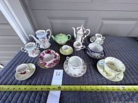 Full lot arranged with 3 tea pots, 7 cups and saucers, and 2 sugar dishes displayed on a grey padded surface.