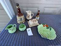Overall shot of the lot showing two Scotch Bell bottles, Wade China creamer and sugar, butter dish, and decorative cabbage plate.