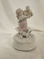 Porcelain figurine of girl holding stack of gifts and dog at base, front view
