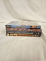 Photo showing spines of four DVD cases stacked horizontally, titles visible, four Western-themed movies
