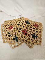 Set of five wooden bead trivets laid flat, showing natural wood beads with red and green colored bead star patterns.