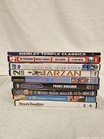 Photo showing side view of 9 DVD cases stacked, titles visible including diverse classic movies.