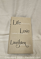 Photo album closed showing beige fabric cover with 'Life Love Laughter' printed text
