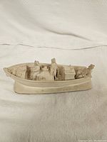 Front view of the carved boat figurine showing detailed figures and boat elements