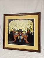 Image of framed print showing figure carrying basket of white calla lilies, artwork clear and centered within frame.