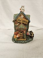 Front view of Halloween-themed post office ceramic figurine showing pumpkin-headed figure, 'Post Office' sign, and small witch figure delivering mail.