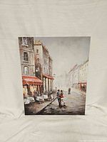 Front view of canvas wall art showing a Paris cafe street scene with people and buildings.