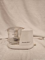 Proctor Silex Mini Food Chopper showing the clear plastic container with blade inside and white motor base.