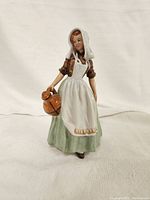 Front view of the Royal Doulton Milkmaid figurine showing the detailed headscarf, apron, and jug held in hand.