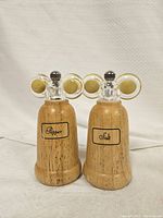 Front view of both salt and pepper shakers showing the labeling and wood grain finish.