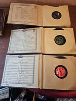 Image of three albums each open to show records in sleeves and an index sheet listing record titles and artists.