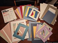 Large assortment of framing mats in multiple colors and sizes fanned out on a table along with the Snapin refill leaves pack.