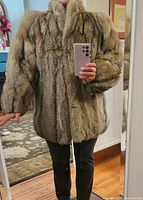 Front view of the fox fur coat showing relaxed arm sleeves, high collar, and natural brown fur texture.