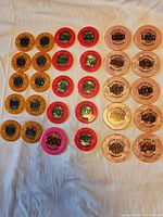 Overview of poker chips laid out on white cloth showing chips of different denominations and colors: orange (100), red and pink (200), and clear pink (1,000).