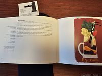 Photo showing an open page of 'The Cocktails of the Ritz Paris' book with an illustrated recipe for Ritz Pimms cocktail, alongside neoprene one bottle tote packaging.