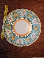 Top view of the 12-inch green terracotta dinner plate with bird and floral border design.