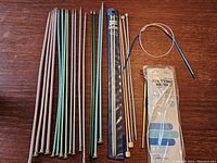 Photo showing a collection of metal and wooden straight knitting needles, circular needles, double-pointed needles, and packaged Boye needles laid out on a wooden surface.