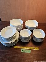 White ceramic plates and bowls arranged on a table showing multiple stacks of each type.
