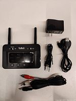 Front view of 1Mii B03 Bluetooth device showing two antennas, LCD screen, and included USB power adapter, USB cable, 3.5mm aux cable, and RCA cable