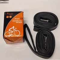 Photo of one inner tube folded beside its original orange and black box packaging labeled 700x35/43C FV48, butyl rubber inner tube for bicycle