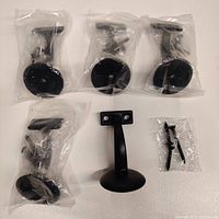 Five oil-rubbed bronze handrail brackets individually bagged, plus a bag of mounting screws. One bracket unpackaged and facing forward.