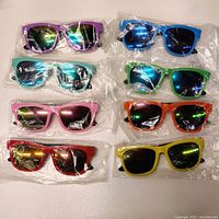 Top-down photo of 8 pairs of child or youth sized sunglasses in sealed plastic packaging arranged in two columns. Frames are various colors with reflective chromatic mirror lenses.