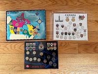 Three Canadian coin sets including provincial quarters and commemorative loonies displayed on wooden floor.