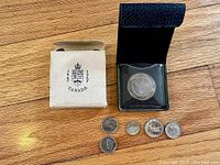 View of all coins and medal in original case with box, placed on wooden surface