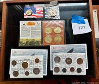 Overview of all coins in the collection shown in a display case, including coin sets and commemorative coins.