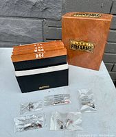 Box and card holder with multiple individually packed firearm lapel pins, labeled with alphabetical dividers