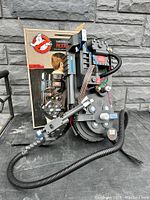 Front view of proton pack replica mounted on display stand with original box in background